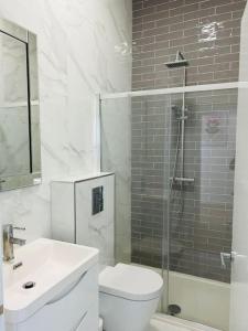 uma casa de banho com um WC, um lavatório e um chuveiro em Elegant 1st Floor 1BR Belsize Park Apartment em Londres
