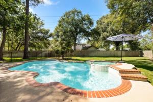 a swimming pool with an umbrella in a yard at 5BR Train Theme Heated Pool Hot Tub EV BBQ in Spring