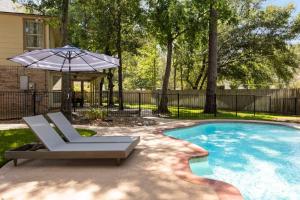 a swimming pool with a chair and an umbrella at 5BR Train Theme Heated Pool Hot Tub EV BBQ in Spring