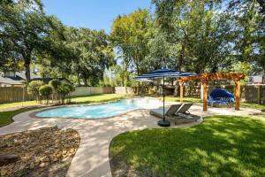 a backyard with a pool and an umbrella and chairs at 5BR Train Theme Heated Pool Hot Tub EV BBQ in Spring