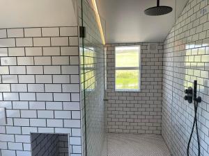 baño con paredes de azulejos blancos y ventana en Hótel Goðafoss Fosshóll en Godafoss