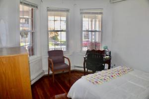 a bedroom with a bed and a chair and windows at West End Haven in Hartford