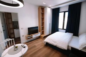 een slaapkamer met een bed en een tafel en een televisie bij Modern Apartments near Center - THE NEST in Tirana