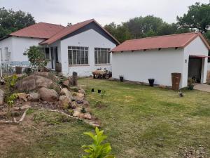 een wit huis met een rood dak en een tuin bij 58 Boom Street Holiday Home. in Parys