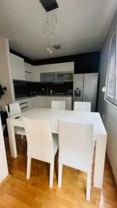 uma cozinha com uma mesa branca e cadeiras brancas em Skopje Centre apartment em Skopje