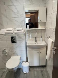 a man taking a picture of a bathroom with a toilet and sink at Апартамент Комфорт, близо до Летището in Sofia