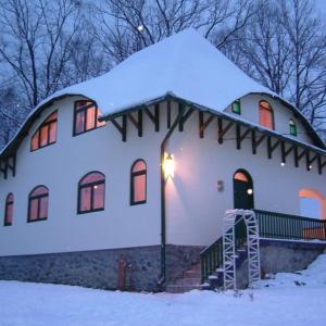 Casa blanca con techo cubierto de nieve en Casă de vacanță Chalet le Cristal, en Sovata