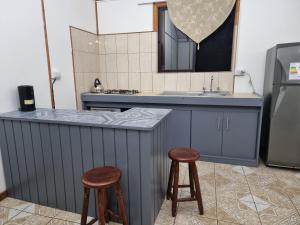 uma cozinha com um balcão com dois bancos e um lavatório em Mika's House em Hanga Roa