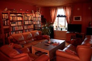 ein Wohnzimmer mit Ledersofas, einem Tisch und Büchern in der Unterkunft Angelas White House in Stamsund