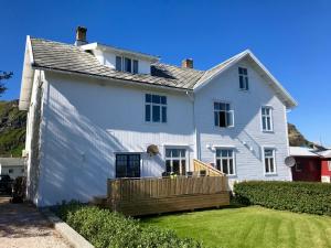 ein weißes Haus mit einer Holzterrasse auf einem Hof in der Unterkunft Angelas White House in Stamsund