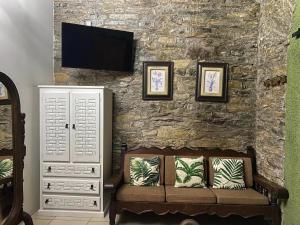 a living room with a couch and a tv on a stone wall at Grann Posada Xilitla in Xilitla
