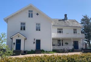 ein weißes Haus mit blauen Türen auf einer Straße in der Unterkunft Angelas White House in Stamsund