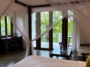 1 dormitorio con cama con dosel, mesa y escritorio en Ceylon Olive Galle en Galle