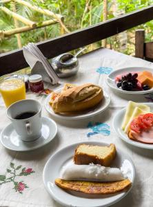a table with plates of breakfast foods and a cup of coffee at Pousada da Fonte in Lençóis