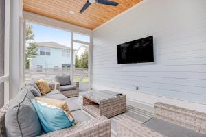 a screened in porch with a couch and a tv at Come Sail Away in Inlet Beach