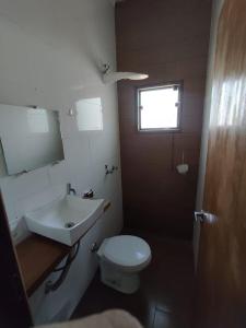 La salle de bains est pourvue d'un lavabo, de toilettes et d'un miroir. dans l'établissement pousada santos, à Jacuí