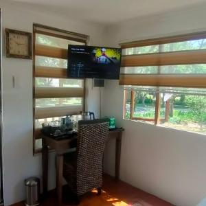 Habitación con escritorio, TV y ventanas. en Lipizzaner Lodge en Kyalami