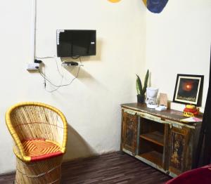 um quarto com uma televisão, uma cadeira e uma secretária em Housetel em Jaipur