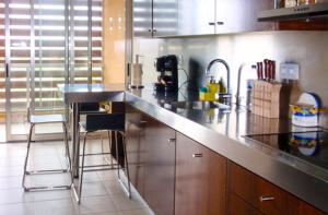 uma cozinha com um balcão com um lavatório e cadeiras em Herdade dos Salgados, T3-11B2A, Vila das Lagoas, Albufeira em Galé