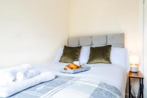a white bed with a tray of towels on it at Beautiful Gloster House with a Large Garden & Free Parking in Woking