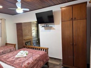 a bedroom with two beds and a flat screen tv at Pousada Recanto das Orquideas in Santo Antônio do Pinhal