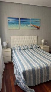 a bedroom with a bed with three paintings on the wall at Jumeke Home in Castro-Urdiales