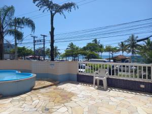 a patio with a tub and a chair on a fence at Apartamento de Frente para o Mar in Ubatuba