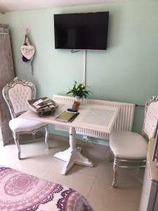 a white desk with two chairs and a tv on a wall at Romantisch Tiny Gardenhouse in beautiful garden in Zandvoort