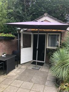 a house with an umbrella on a patio at Romantisch Tiny Gardenhouse in beautiful garden in Zandvoort