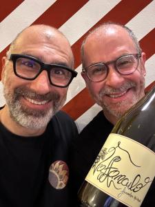 Due uomini con gli occhiali in piedi accanto a una bottiglia di vino. di Il Girasole High Quality Inn a Milano