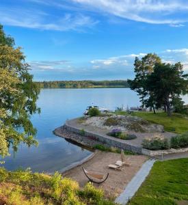 vistas a un lago con 2 sillas en la orilla en Bastuviken Bed and Breakfast en Uppsala