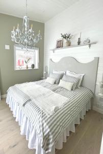 a bedroom with a large white bed with a chandelier at Bastuviken Bed and Breakfast in Uppsala