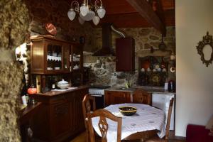 a kitchen with a table and a stove and a counter top at Casinha Estrela da Encosta - Gerês in Vieira do Minho
