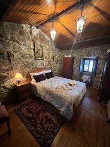 1 dormitorio con cama y pared de piedra en Casinha Estrela da Encosta - Gerês en Vieira do Minho