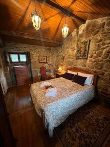 ein Schlafzimmer mit einem großen Bett und einer Steinmauer in der Unterkunft Casinha Estrela da Encosta - Gerês in Vieira do Minho