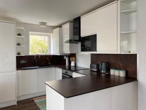 a kitchen with white cabinets and a black counter top at Two Bedroom apartment with river view in London