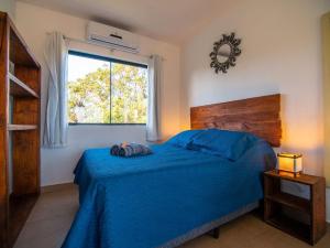 Un dormitorio con una cama azul y una ventana en Lugar ao Sol - Flats - Praia do Rosa - SC en Praia do Rosa
