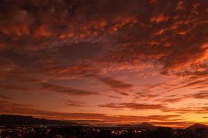 um pôr-do-sol sobre uma cidade com um céu nublado em Lugar ao Sol - Flats - Praia do Rosa - SC em Praia do Rosa