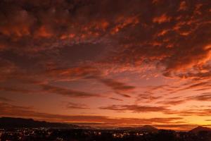 a sunset over a city with a cloudy sky at Lugar ao Sol - Flats - Praia do Rosa - SC in Praia do Rosa