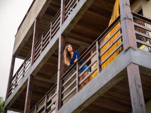 una mujer mirando desde un balcón de un edificio en Lugar ao Sol - Flats - Praia do Rosa - SC en Praia do Rosa