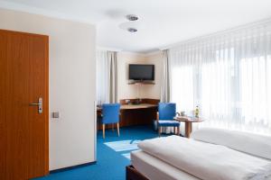 a hotel room with a bed and a desk and a television at Garni-Hotel Sailer & Hotel Sailer´s Villa in Rottweil