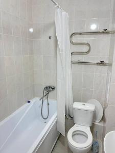 a white bathroom with a toilet and a bath tub at Апартаменты на Туране в Алтын Шар in Taldykolʼ