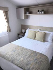 uma grande cama branca num quarto com uma janela em Sea breeze, modern, cosy holiday home(Wi-Fi) em Millom