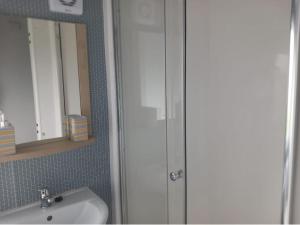 uma casa de banho com um chuveiro, um lavatório e um espelho. em Sea breeze, modern, cosy holiday home(Wi-Fi) em Millom