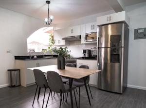 a kitchen with a table and a stainless steel refrigerator at Apartamento acogedor y minimalista. in Quetzaltenango