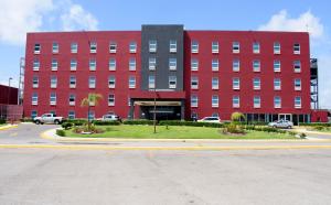 un grand bâtiment rouge avec des voitures garées devant lui dans l'établissement Los Herederos Hotel Piedras Negras, 