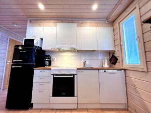a kitchen with white cabinets and a black refrigerator at Himoskuikka in Jämsä