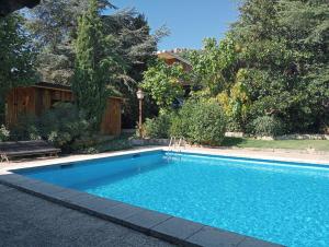 a swimming pool in a yard with a bench at Jardín Las Secuoyas in Becerril de la Sierra