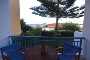 a table and chairs on a balcony with a palm tree at Athena Kythera in Dhiakofti