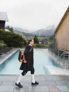 a man walking down a sidewalk holding aophone at Bio-Hotel Oswalda-Hus in Riezlern